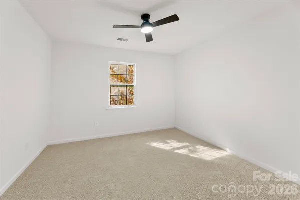 an empty room with a window and a ceiling fan