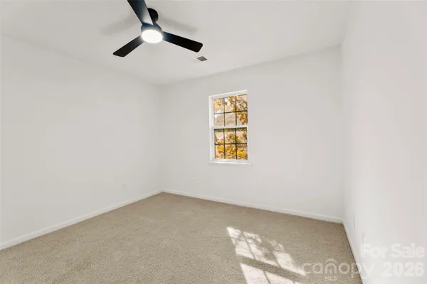 an empty room with windows and ceiling fan