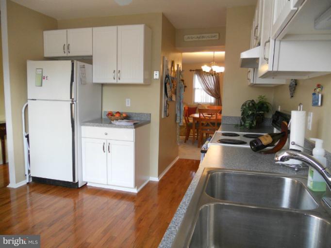 9321 Pan Ridge Road, Unit 9321 Parkville, MD 21234 - Photo 14 of 30 a kitchen with stainless steel appliances a stove a refrigerator a sink a cabinets and wooden floor