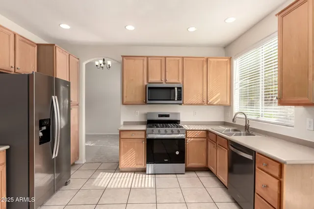 a kitchen with stainless steel appliances granite countertop a refrigerator a sink a stove top oven and a window