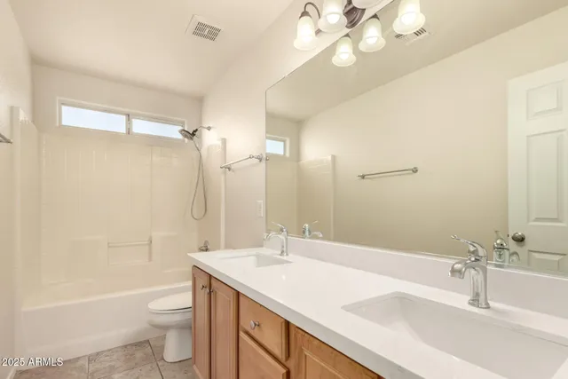 a bathroom with a granite countertop sink a toilet a mirror a bathtub and shower