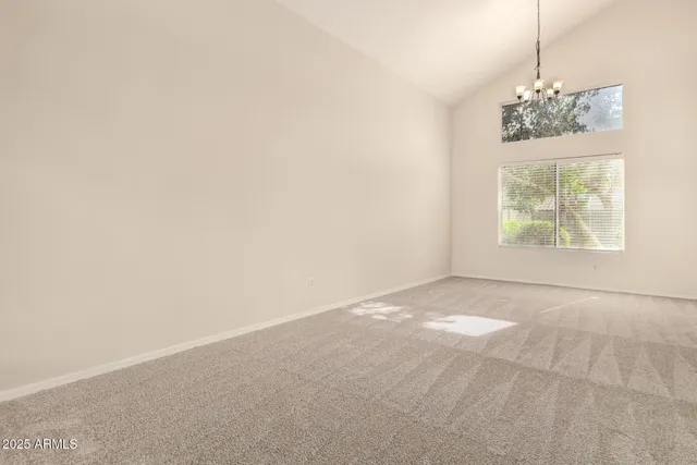 an empty room with windows and chandelier fan