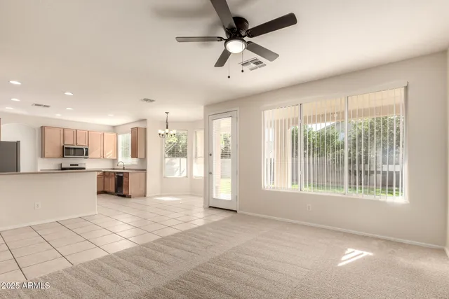 a view of an empty room with kitchen view and a window