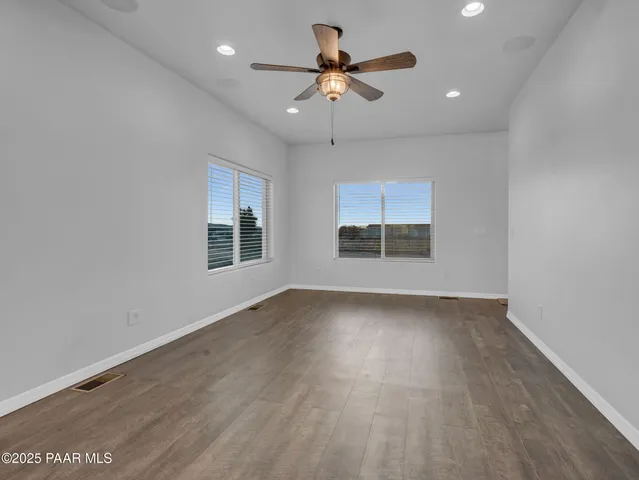 an empty room with wooden floor chandelier and windows