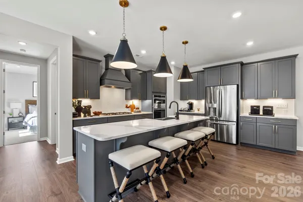 a kitchen with stainless steel appliances granite countertop a sink a stove a refrigerator and wooden floor