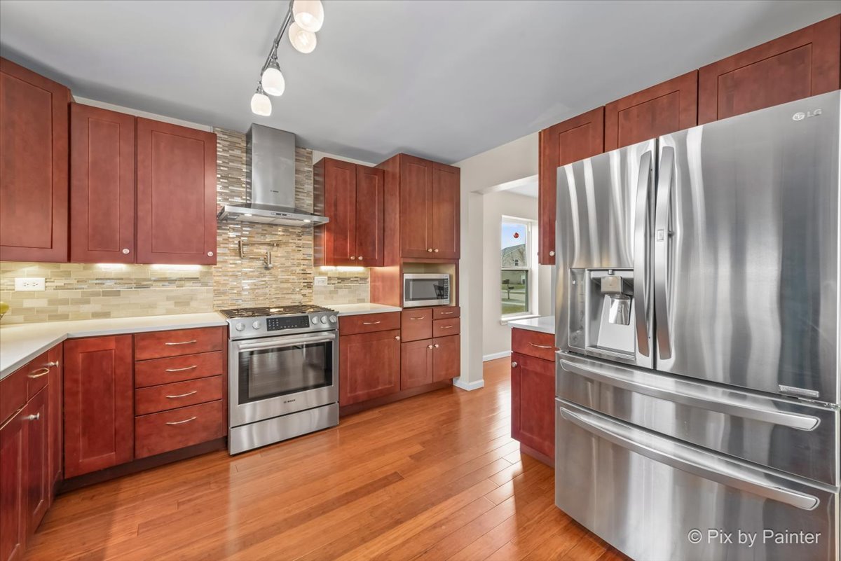 4902 Stillwater Road Wonder Lake, IL 60097 - Photo 12 of 46 a kitchen with stainless steel appliances granite countertop a refrigerator oven a sink dishwasher and wooden cabinets with wooden floor