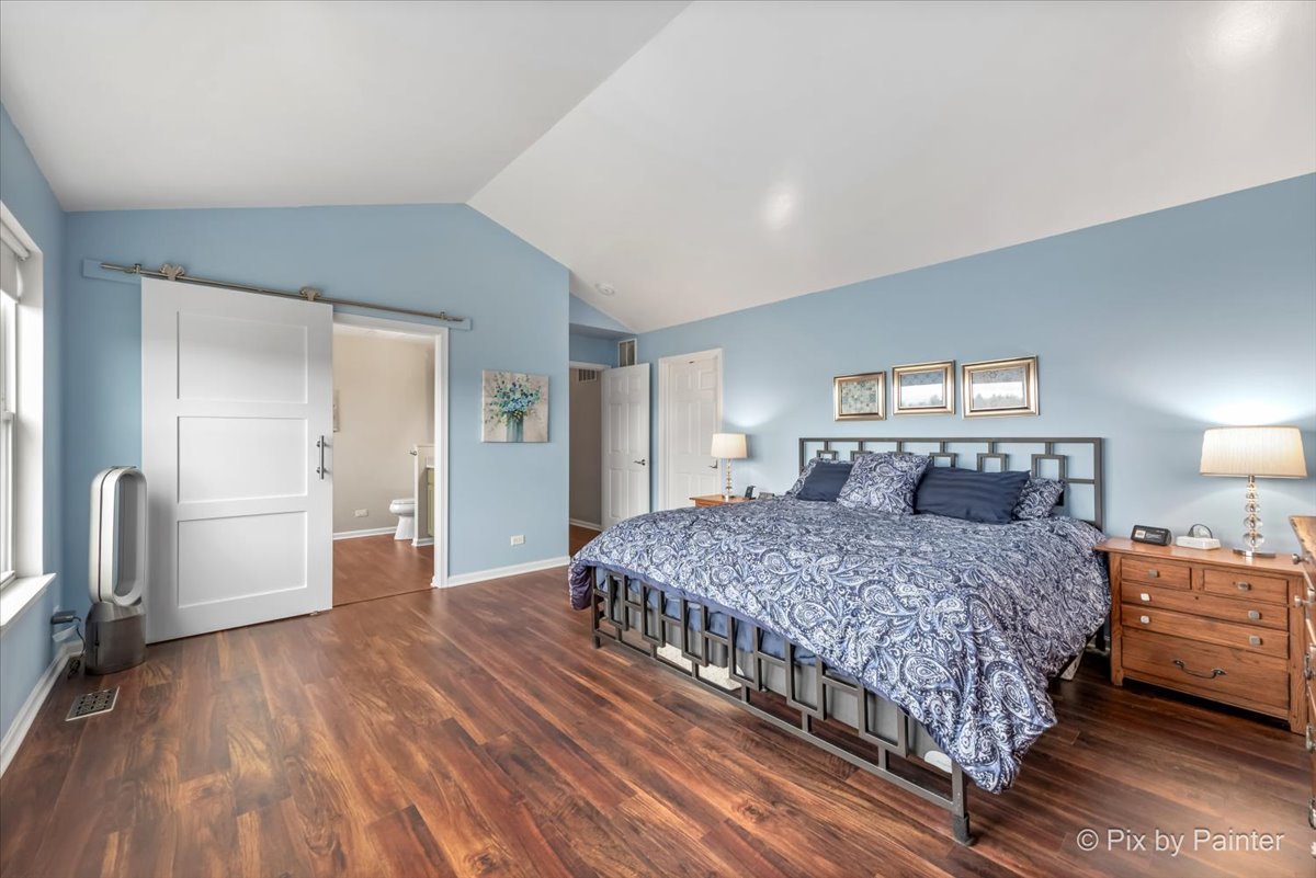 4902 Stillwater Road Wonder Lake, IL 60097 - Photo 28 of 46 a bedroom with a large bed and a chandelier