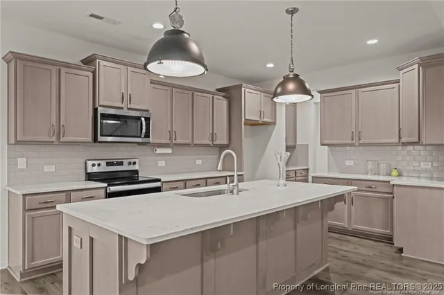 a kitchen with stainless steel appliances a sink a stove a microwave and cabinets