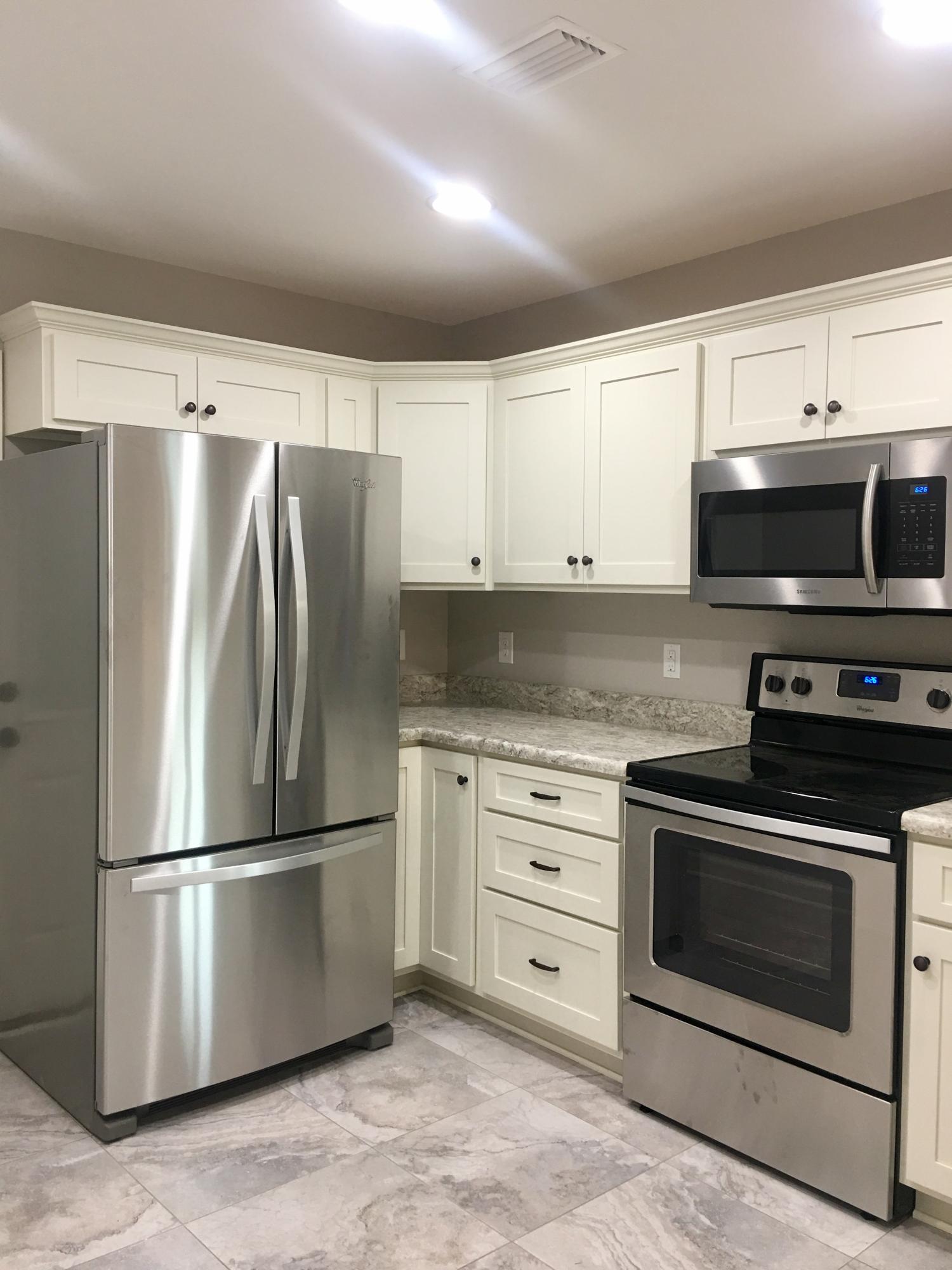 976 Valley Road Crestview, FL 32539 - Photo 4 of 26 a kitchen with stainless steel appliances white cabinets white stove a refrigerator and a microwave