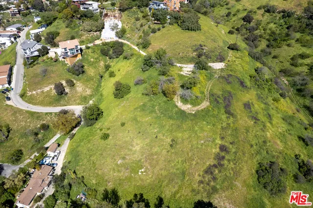 an aerial view of residential houses with outdoor space and trees