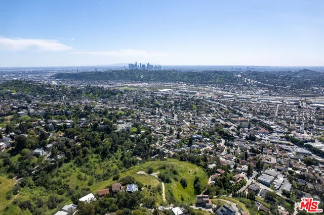 an aerial view of a residential houses with outdoor space and trees