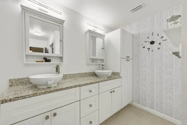 a bathroom with a granite countertop double vanity sink a mirror and a shower