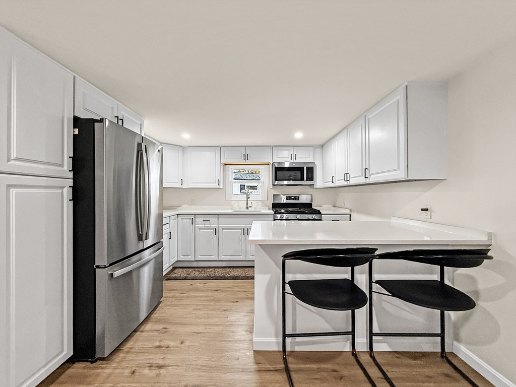126 Beach Road Salisbury, MA 01952 - Photo 12 of 30 a kitchen with stainless steel appliances granite countertop a refrigerator a sink dishwasher a stove and white countertops with wooden floor