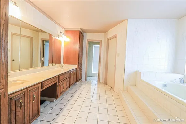 a large bathroom with a tub a sink and a large mirror