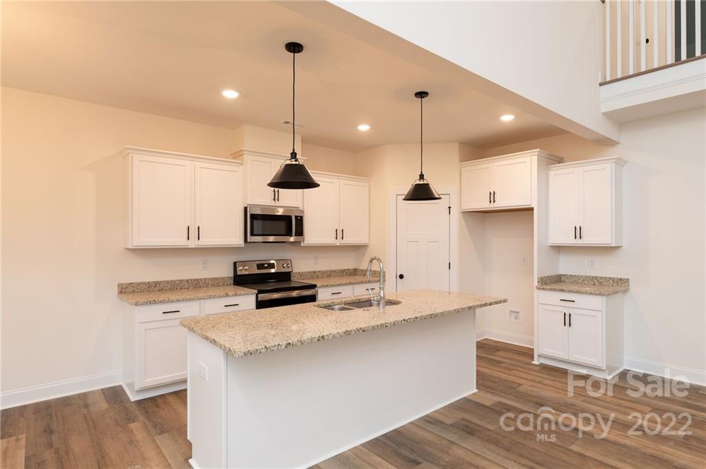 2217 State Rd S-46-1474, Unit 15 Clover, SC 29710 - Photo 32 of 39 a kitchen with stainless steel appliances kitchen island granite countertop a sink a stove and a refrigerator