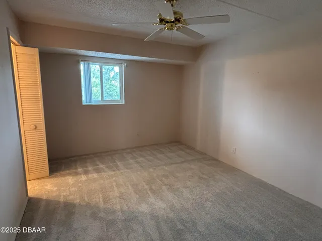 an empty room with windows and fan