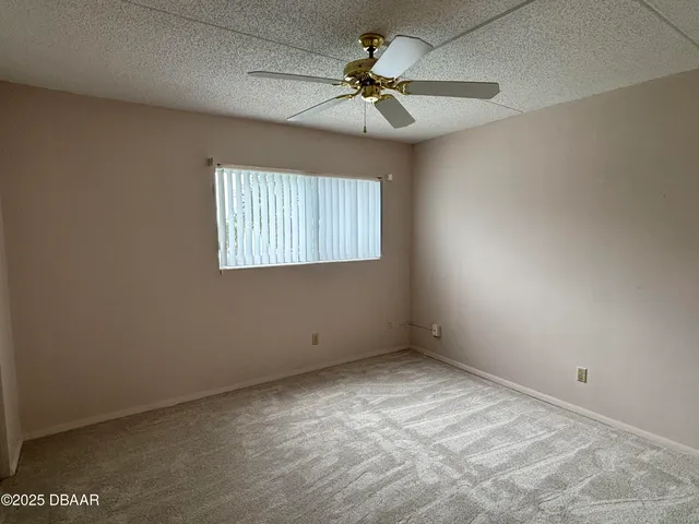 an empty room with a window and a ceiling fan