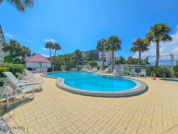 a view of a swimming pool with lawn chairs under an umbrella