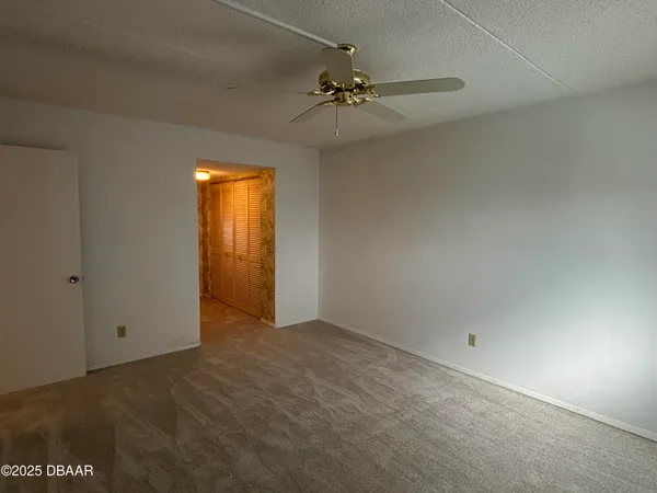 an empty room with a chandelier fan and closet