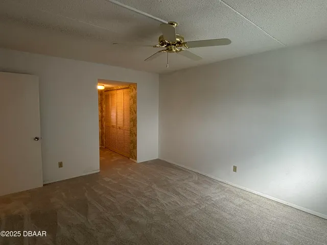 an empty room with a chandelier fan and closet