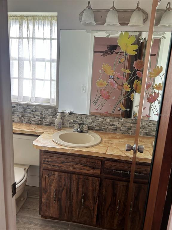 8511 Longboat Lane Hudson, FL 34667 - Photo 15 of 17 a bathroom with a granite countertop sink a toilet and a window