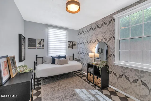 a bedroom with a bed a mirror and a flat tv screen on the dresser