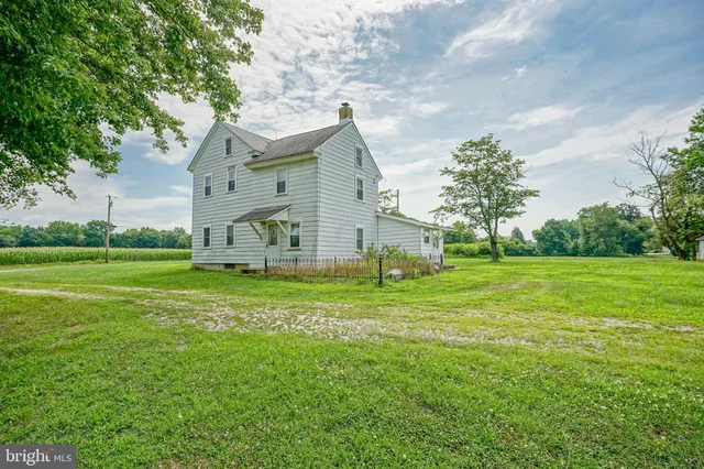 a view of a house with a big yard and large trees