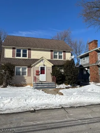 a front view of a house with a yard covered with snow