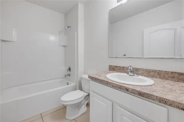 an empty room with a chandelier fan and windows