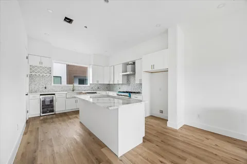 a kitchen with cabinets wooden floor and stainless steel appliances