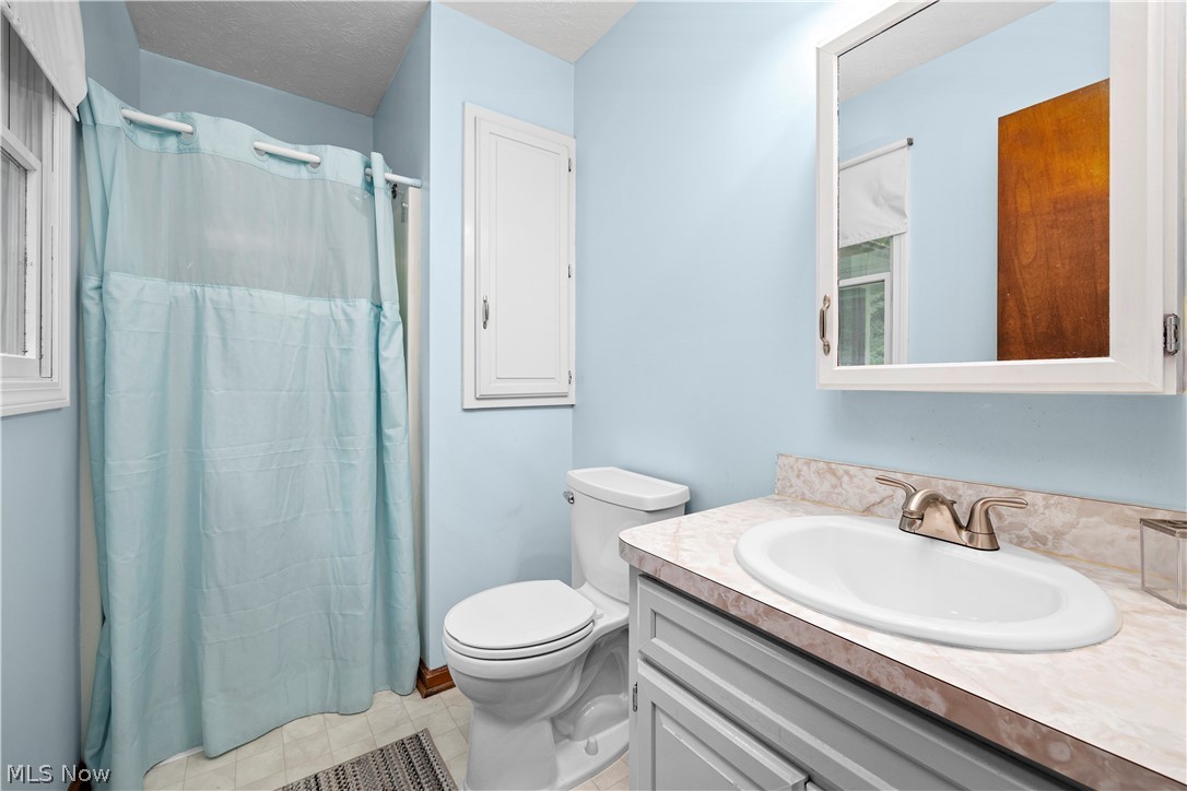 6211 Russia Road Amherst, OH 44001 - Photo 21 of 50 Bathroom with tile flooring, a textured ceiling, oversized vanity, and toilet