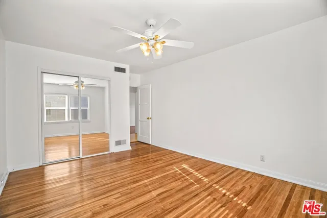 a view of empty room with wooden floor and fan