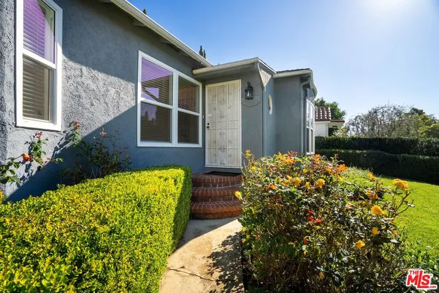 a front view of a house with a yard and potted plants