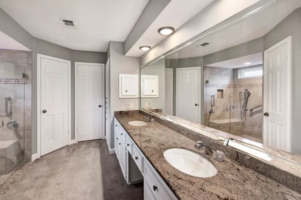 a bathroom with a granite countertop double vanity sink and a mirror