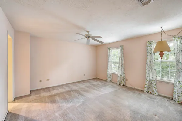 an empty room with windows and fan