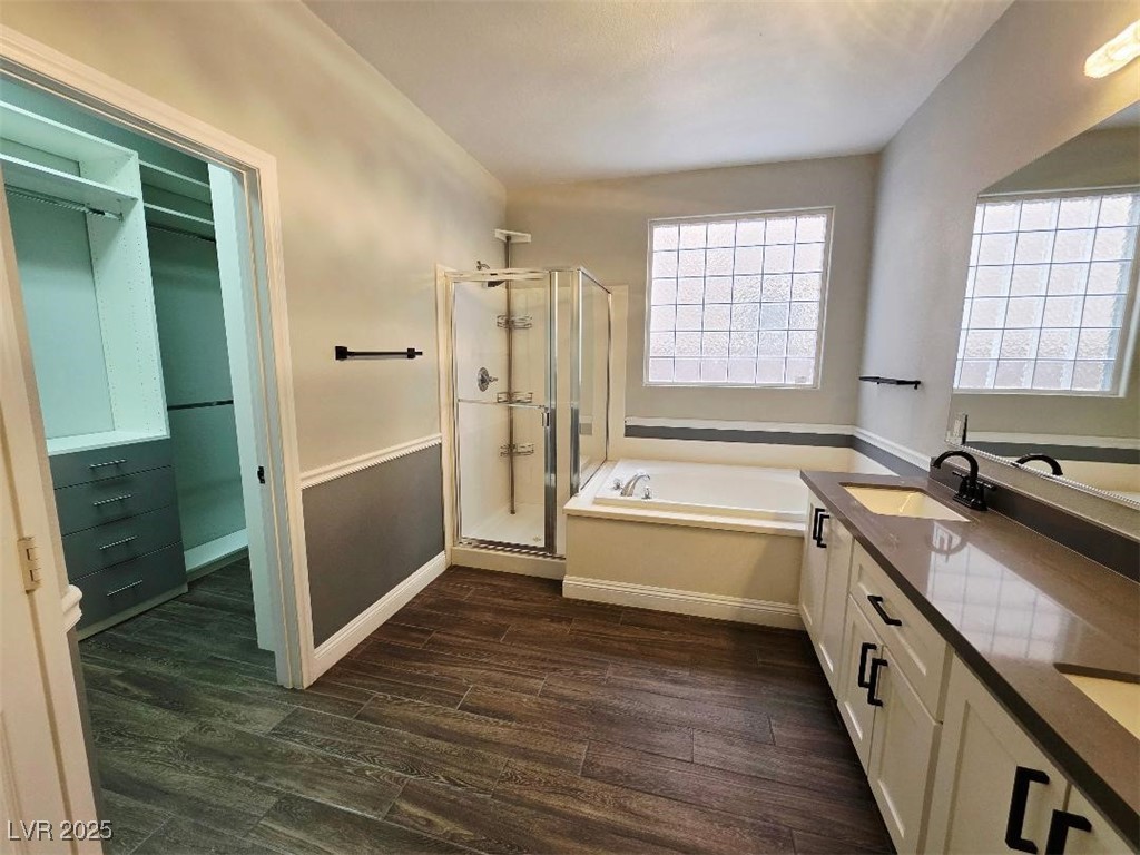 7055 Fort Tule Avenue Las Vegas, NV 89179 - Photo 64 of 75 Full bath with a spacious closet, double vanity, a shower stall, a garden tub, and dark tile-style flooring down 2nd primary bedroom