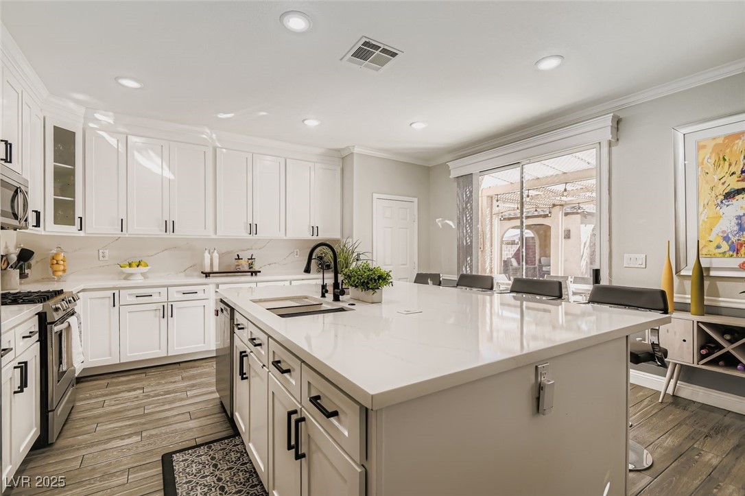 7055 Fort Tule Avenue Las Vegas, NV 89179 - Photo 9 of 75 Kitchen featuring a center island with sink, appliances with stainless steel finishes, light tile finished floors, backsplash, and recessed lighting