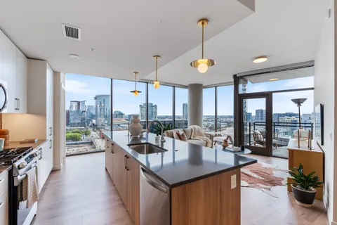 a kitchen with counter top space a sink appliances and a large window