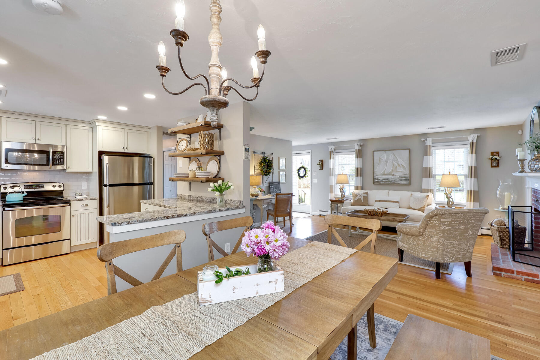 53 Kelley Road West Harwich, MA 02671 - Photo 14 of 43 a view of a dining room and livingroom with furniture wooden floor a rug a chandelier