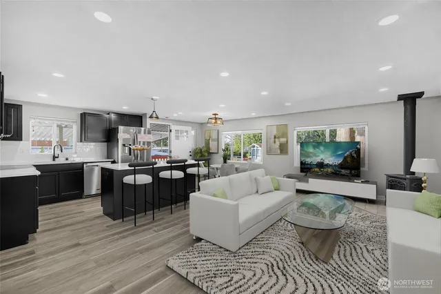 a living room with furniture kitchen view and a wooden floor