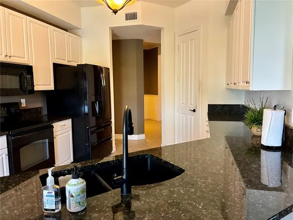 a kitchen with granite countertop white cabinets and stainless steel appliances