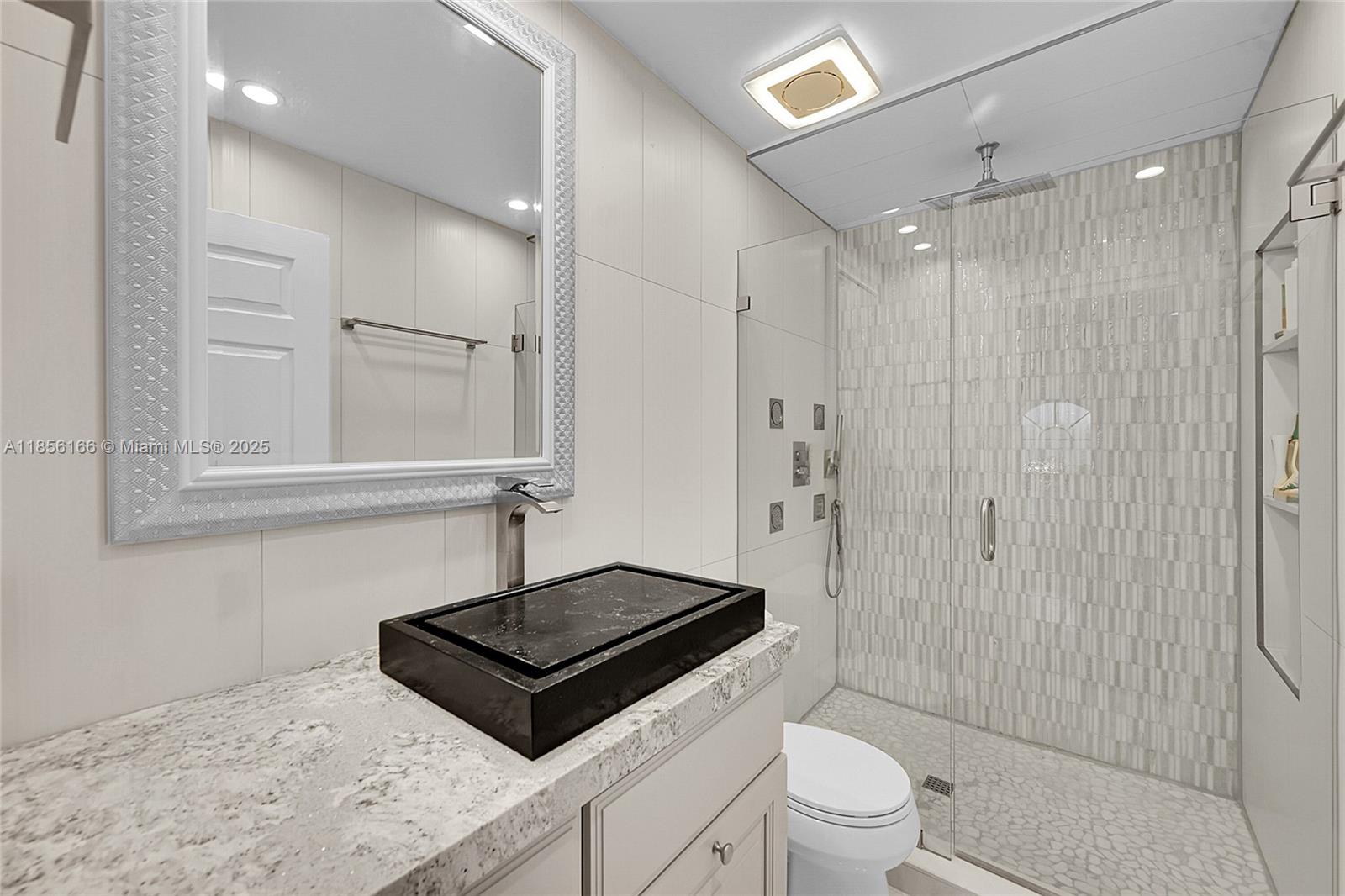 9398 Aegean Drive Boca Raton, FL 33496 - Photo 33 of 61 a bathroom with a sink a toilet a mirror and shower