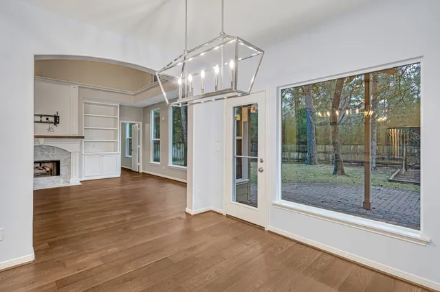 a view of a room with wooden floor a fireplace a chandelier and windows