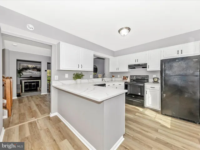 a kitchen with a sink a stove a refrigerator and white cabinets