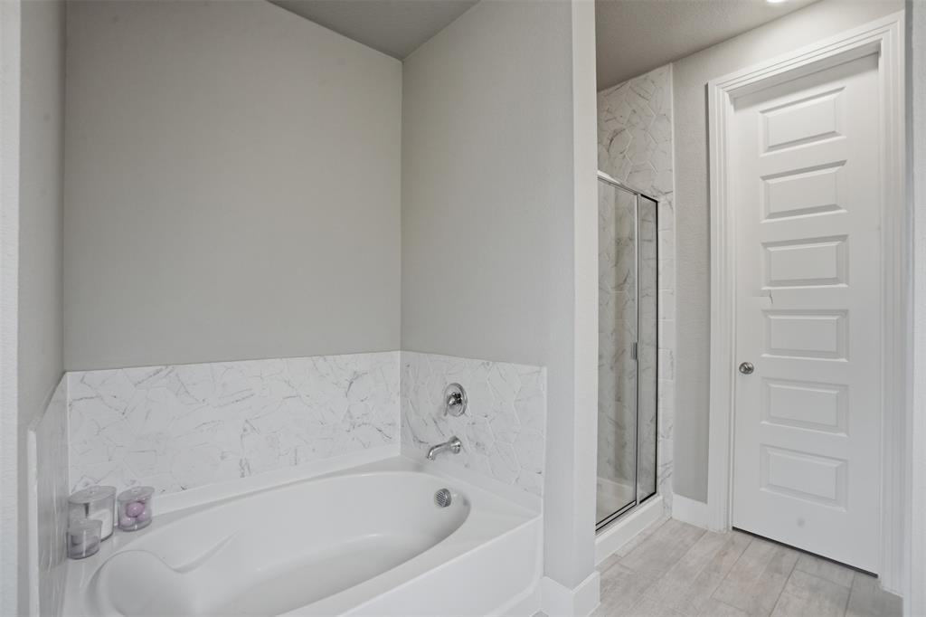 1429 Eclipse Road Aubrey, TX 76227 - Photo 15 of 37 The bathroom features a built-in tub with a tiled surround, a separate glass-enclosed shower, and a paneled door