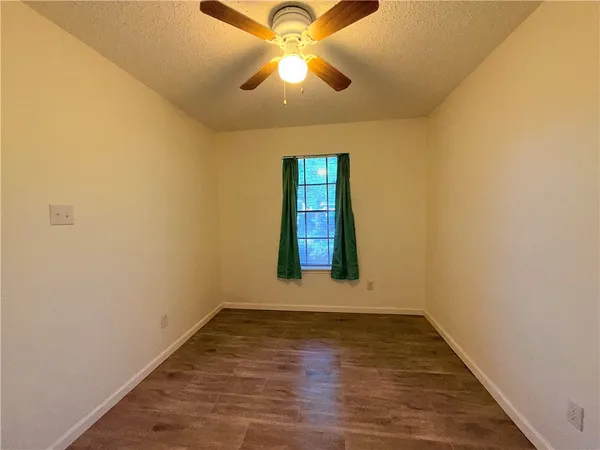 a view of an empty room with window and wooden floor