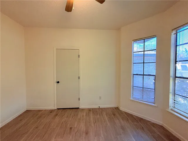 a view of an empty room with window and wooden floor