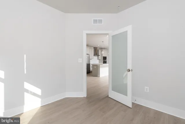 a view of a hallway with wooden floor and a bathroom
