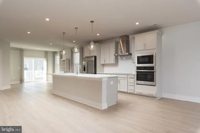 a large kitchen with stainless steel appliances kitchen island granite countertop a large counter top a oven and a sink