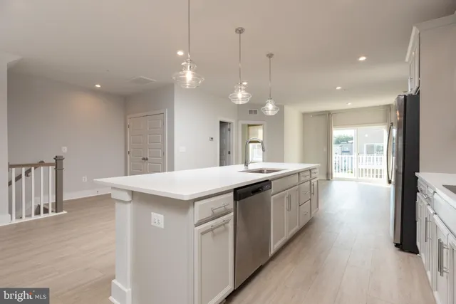 a large kitchen with kitchen island a sink stainless steel appliances and a chandelier